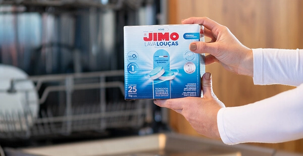 Pessoa segurando embalagem do JIMO Lava-Louças multicamadas, com 25 pastilhas para máquina de lavar louças, destacando tecnologia contra sujeiras difíceis.