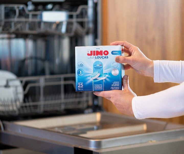 Pessoa segurando embalagem do JIMO Lava-Louças multicamadas, com 25 pastilhas para máquina de lavar louças, destacando tecnologia contra sujeiras difíceis.