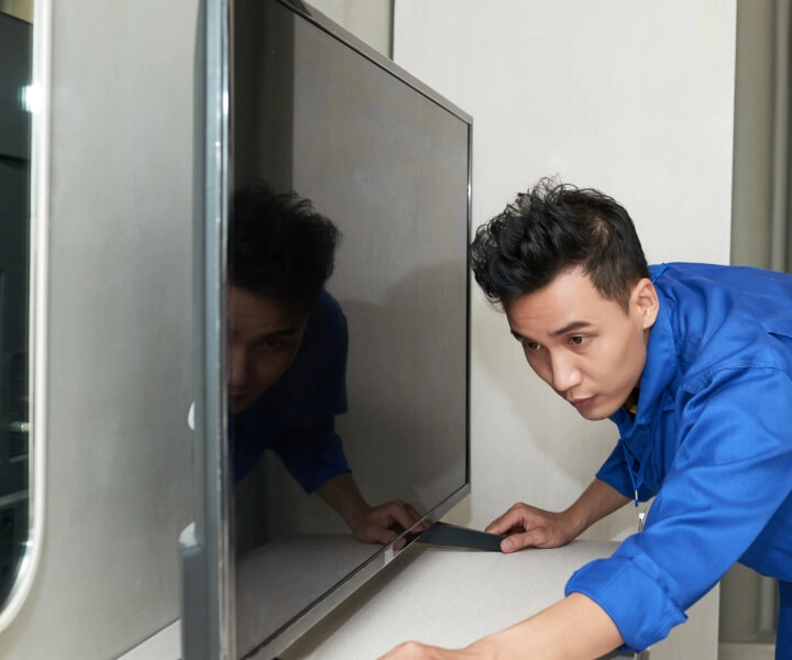 Pessoa ajustando uma TV de tela plana sobre um móvel em um quarto